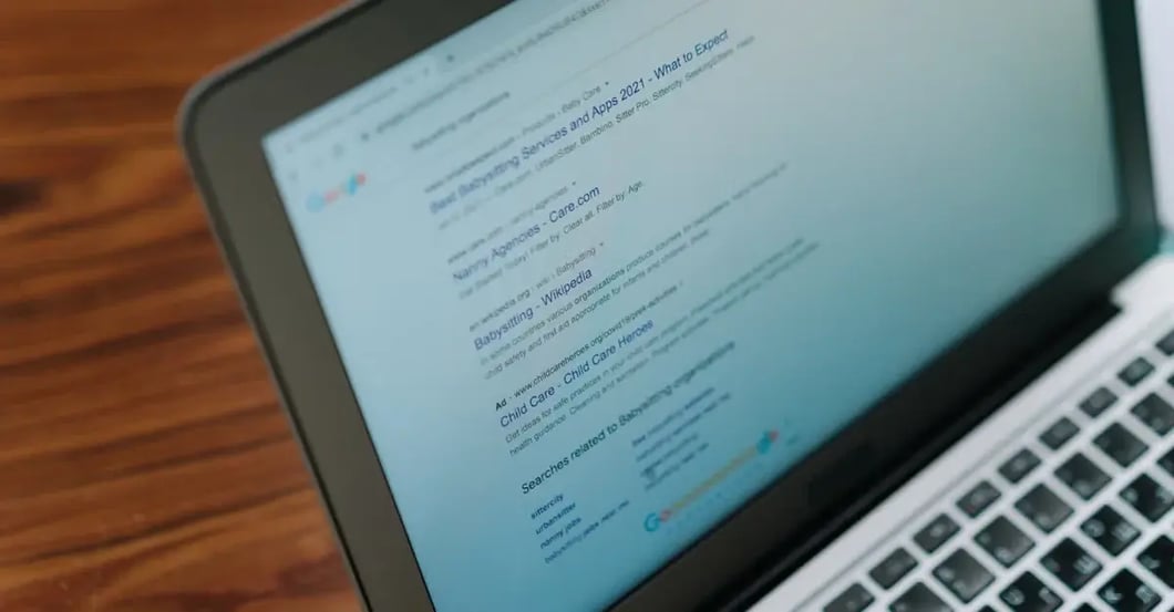 Laptop screen displaying Amazon keyword research results and data analysis on wooden desk.