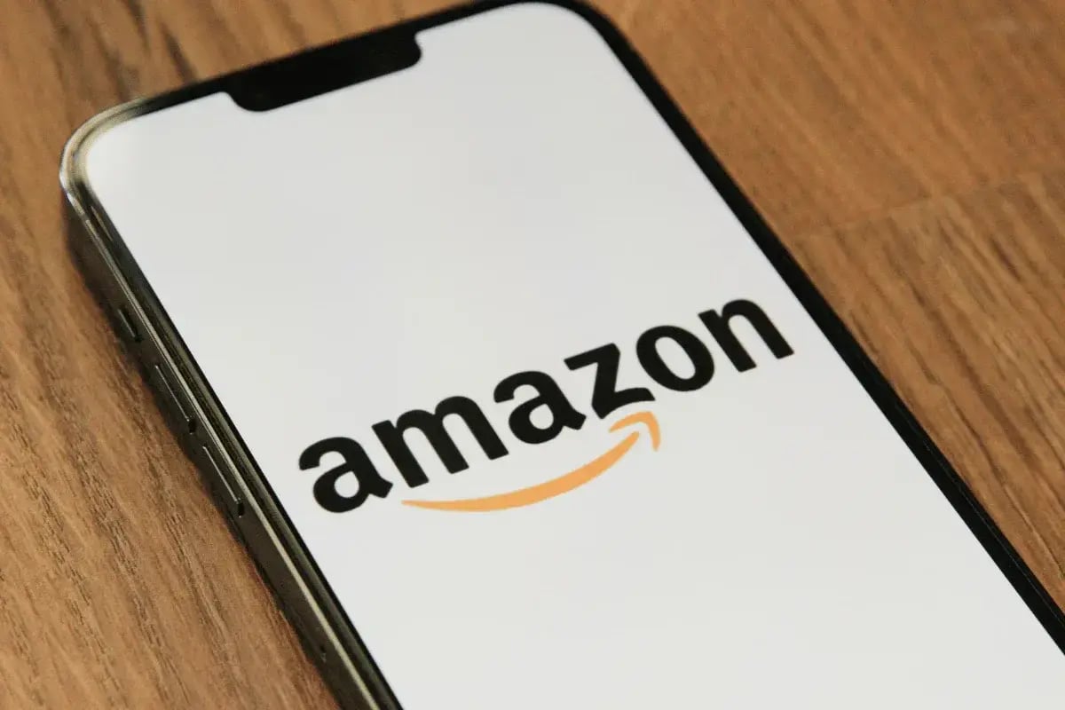 Smartphone displaying the Amazon logo on its screen, resting on a wooden surface.