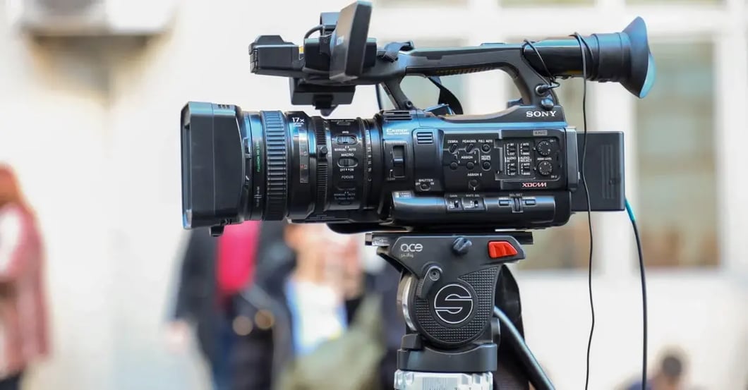 Professional video camera mounted on tripod filming amazon listing video content outdoors with blurred background.
