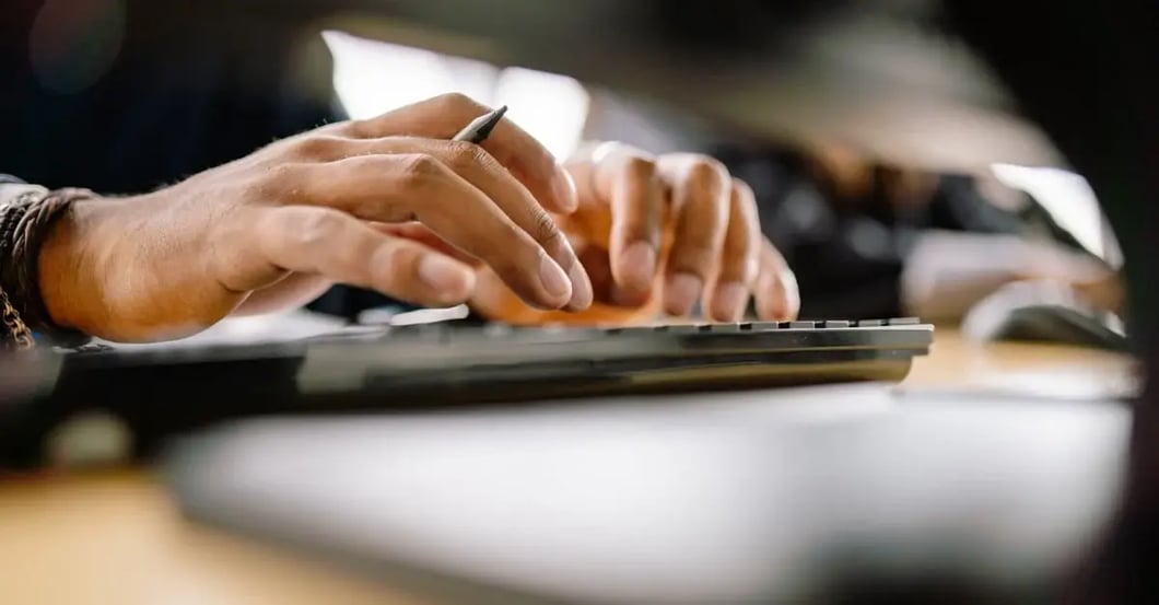 Hands typing on keyboard while managing amazon product variations on computer screen with documents.