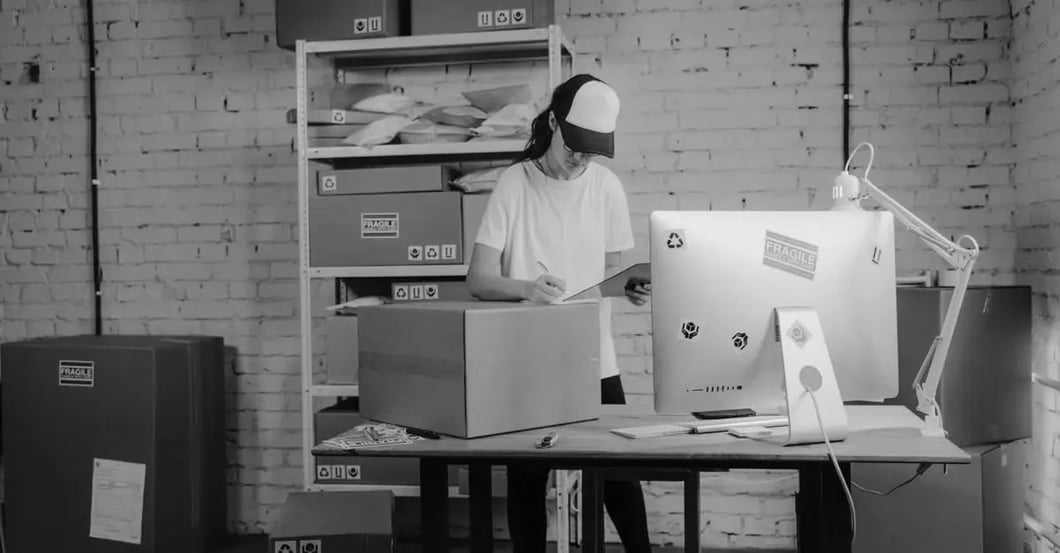 Worker wearing safety gear organizing Amazon restricted products in organized storage bins and shelves in warehouse.