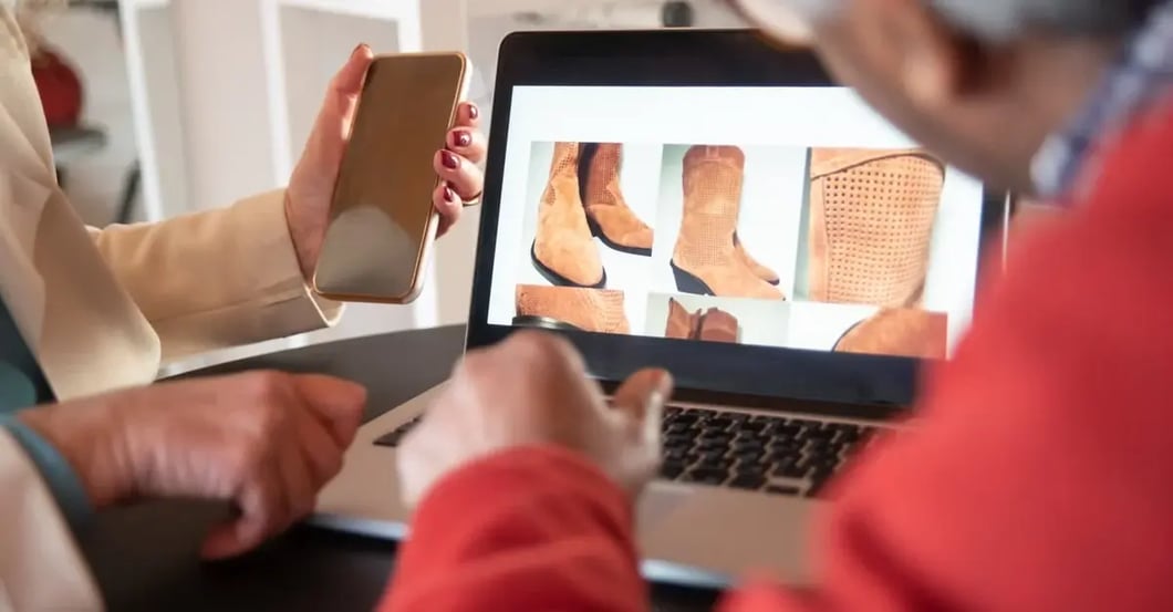 Two people discussing product bundling strategy with shoe options displayed on laptop screen and tablet.