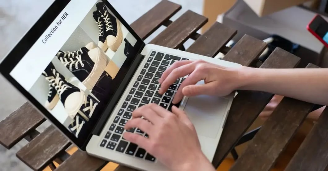 Hands typing on laptop displaying shoe product listings for amazon ppc optimization campaign management.