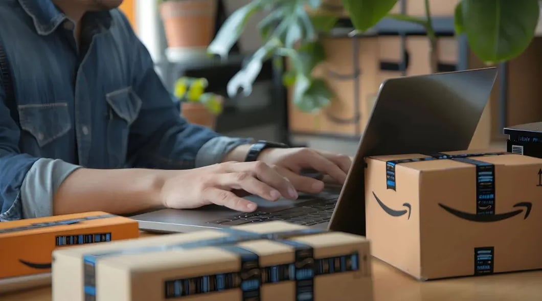 Amazon seller packing products while working on a laptop.