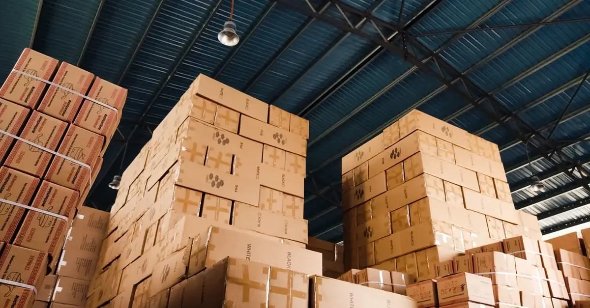 Cardboard boxes stacked in warehouse showing excess Amazon stranded inventory stored under metal roof structure.