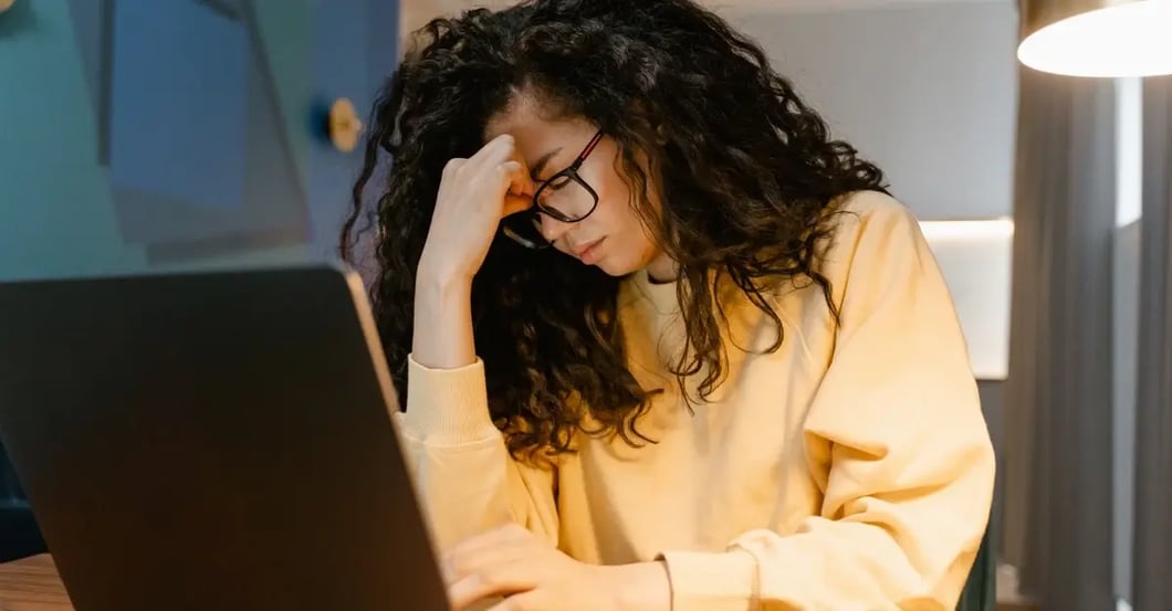 Woman with Amazon section 3 violation concerns stressed at laptop, contemplating next steps for account recovery.