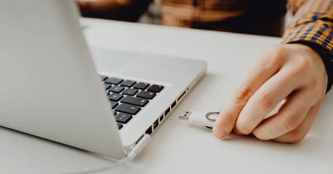 Person using laptop with USB drive connected, selecting amazon flat files template for product data management.