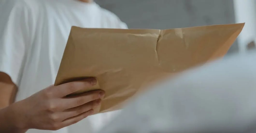 A person holding brown cardboard box, demonstrating how to report listing amazon concerns for suspicious packages.
