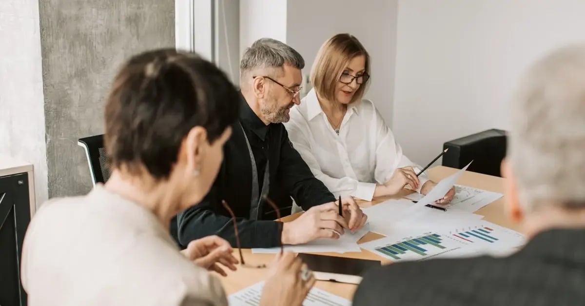 Team members reviewing amazon stranded inventory reports and financial charts during collaborative business meeting at table.