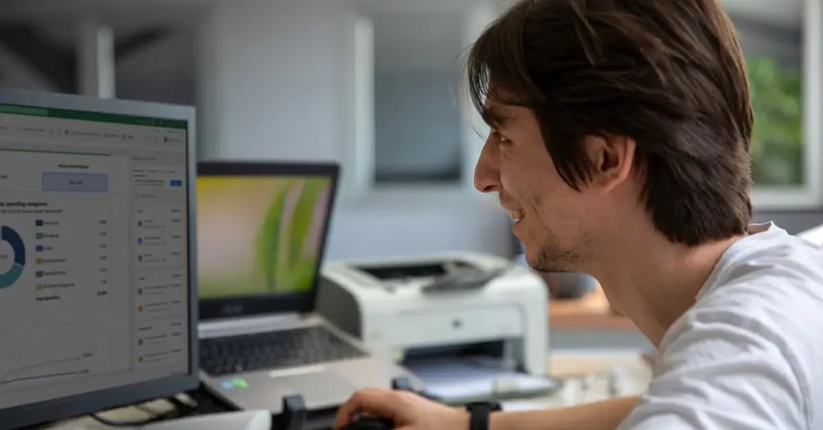 Man analyzing Amazon seller dashboard with analytics data on desktop monitor in modern office workspace.