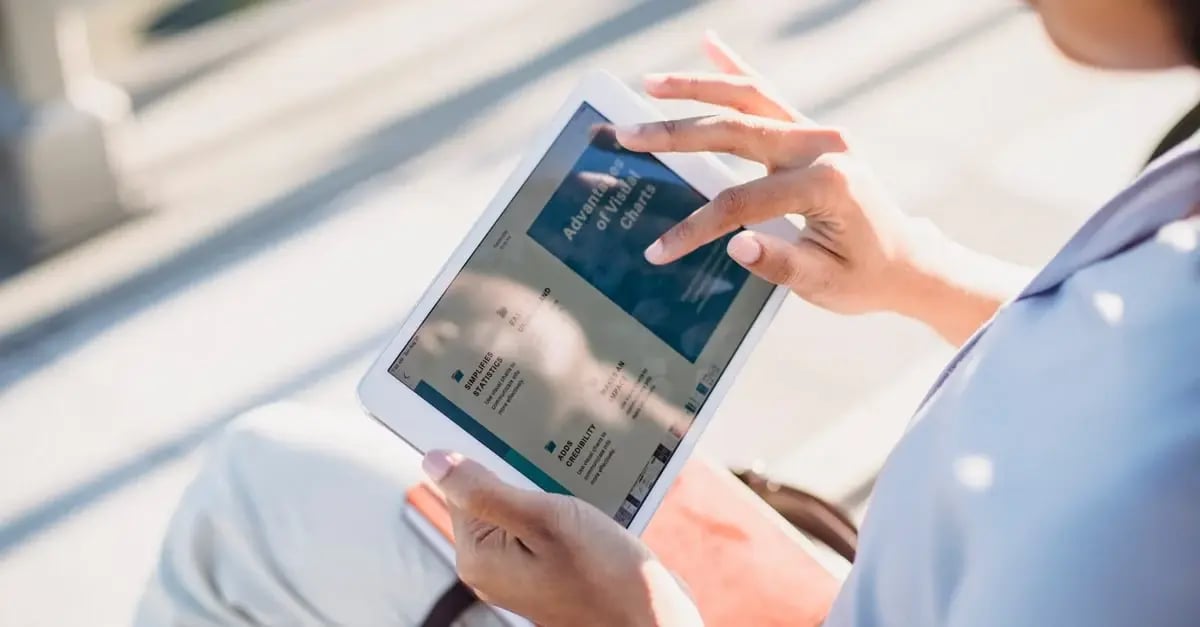 Person holding tablet displaying amazon listing video content on bright outdoor screen.